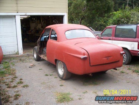 red coupe project car in front of garage, another SUV parked behind it