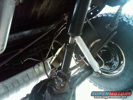 Underside view of a vehicle's driveshaft, U-joint, leaf springs, shock absorber, and rear axle