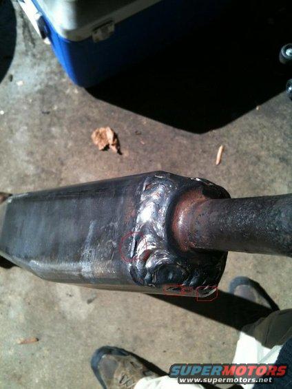 Exhaust pipe with heavy welds and a blue and white cooler in the background