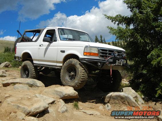 White 1996 Ford Bronco with off-road modifications navigating rocks