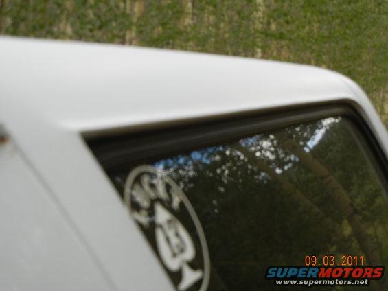 Close-up of white SUV roof and window with a circular sticker and date overlay