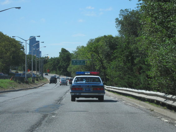 Police car driving on highway, sign says W 95 St Exit 1/2 Mile