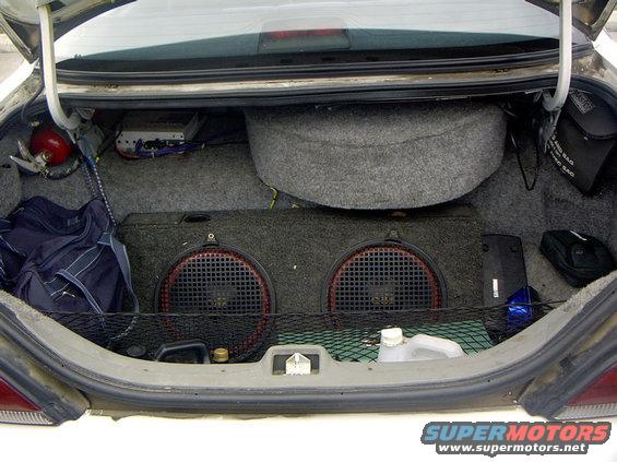 Car trunk with two subwoofers, spare tire, and an amplifier