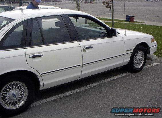 White sedan parked in a lot, side view showing doors and wheels