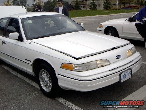 White 1999 Ford Crown Victoria front view, hood open. Another white Crown Victoria visible