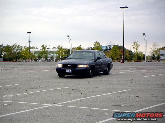 dark sedan parked in an empty lot, front view