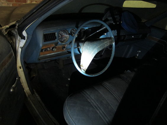 Interior view of a blue dashboard and steering wheel in a vintage car