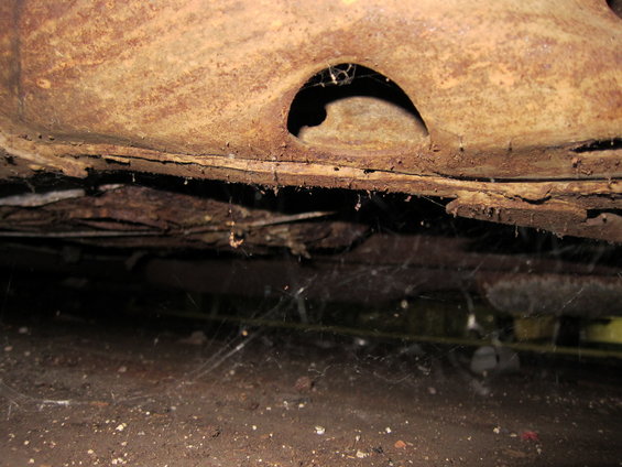 Rusted undercarriage with cobwebs and debris