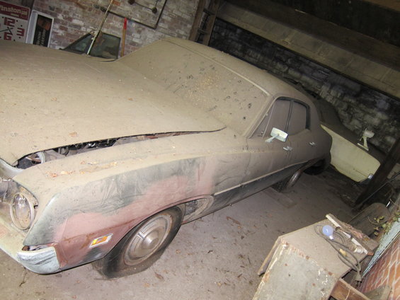 Dusty car in a garage, hood up, another car behind it