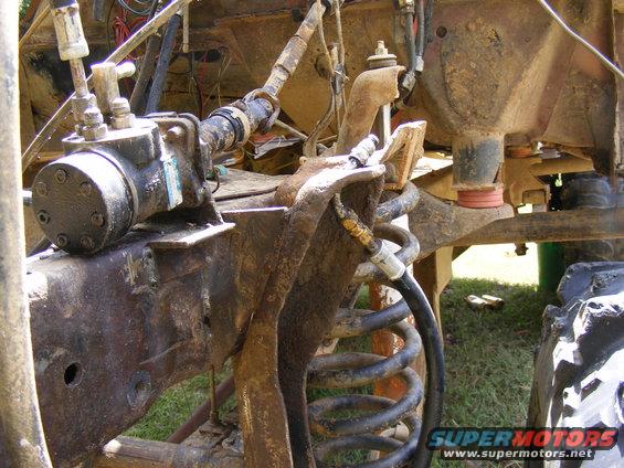 close-up of rusty off-road vehicle suspension with hydraulic lines and coil spring