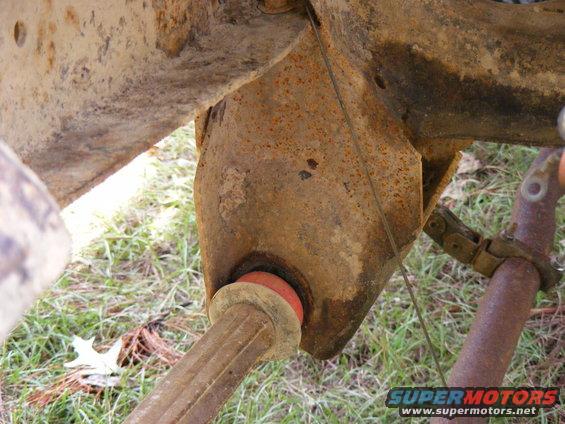 Rusty suspension part with red bushing and metal clamp