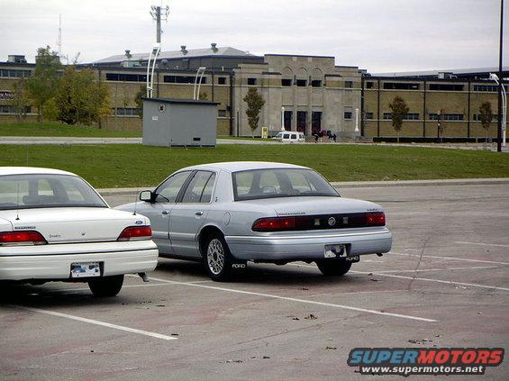 Silver sedan parked in a lot, rear view. Mud flaps say "FORD"