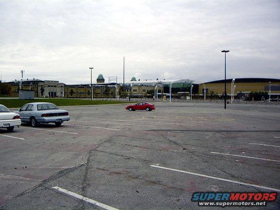 Red coupe parked in a large, empty parking lot