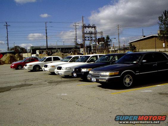 Several Ford Crown Victoria Police Interceptors and a Mercury Grand Marquis parked in a lot