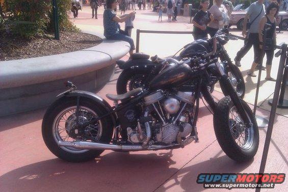 Black custom motorcycle with spoked wheels and a visible engine, parked outdoors