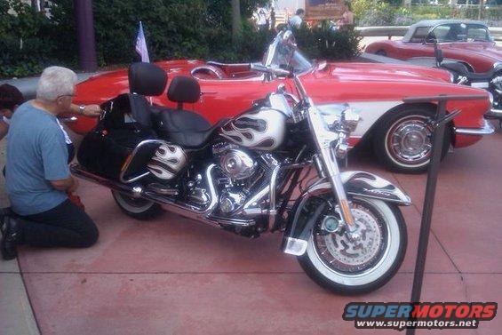 Motorcycle with flame decals parked next to a red classic car