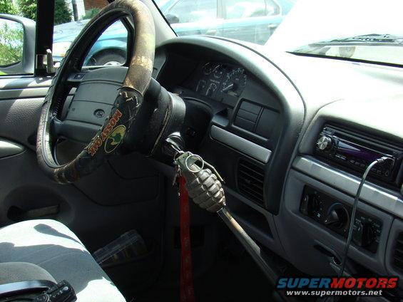 Truck interior showing steering wheel with Mossy Oak cover, dashboard, and a grenade shift knob