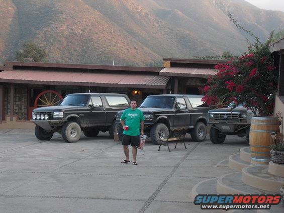 Three black Ford Bronco SUVs parked outside a building with a man standing in front of the middle one