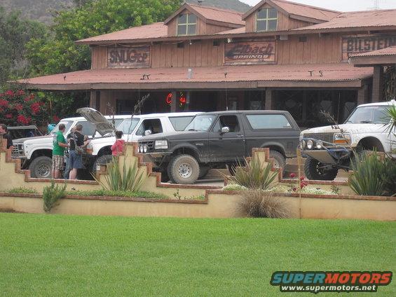 Black 1987 Ford Bronco parked in front of a building with "Eibach Springs" sign
