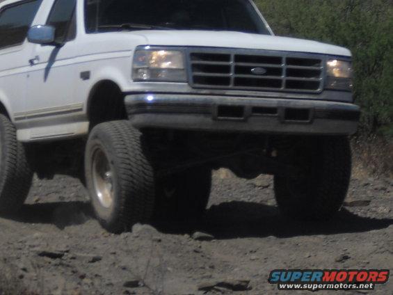 White SUV with prominent grille and headlights driving off-road