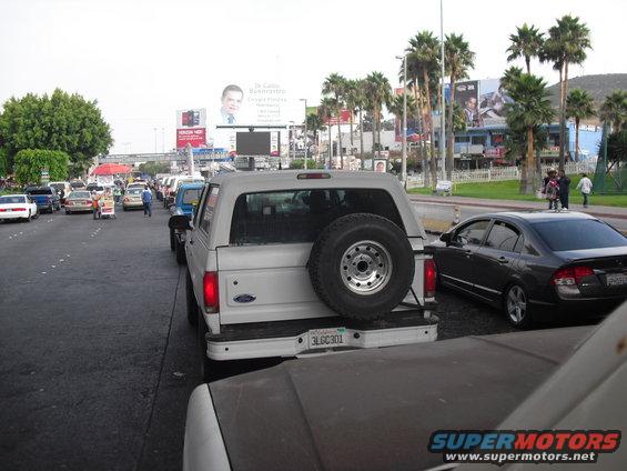 White Ford Bronco with spare tire on rear bumper, in traffic