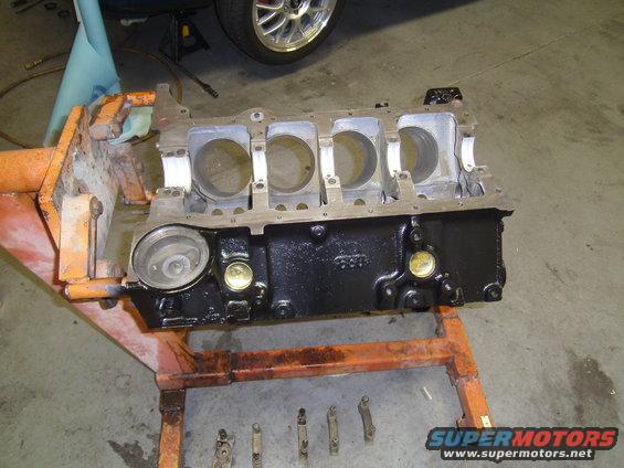 Engine block on an orange stand. Some parts are laid out below it