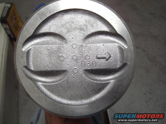 Close-up of an engine piston with '030' and an arrow stamped on it