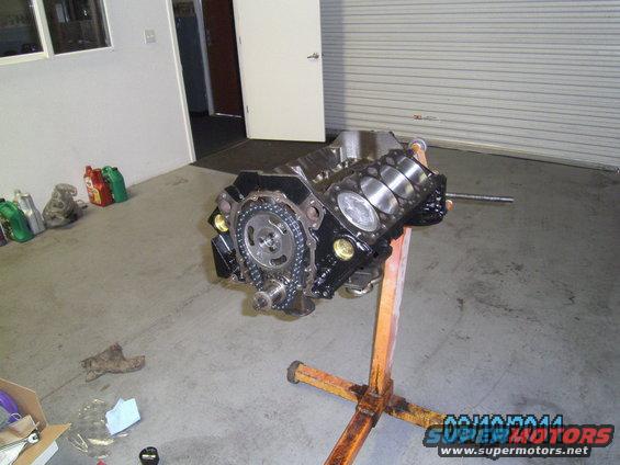 Engine block on an orange engine stand, with timing chain and gears visible