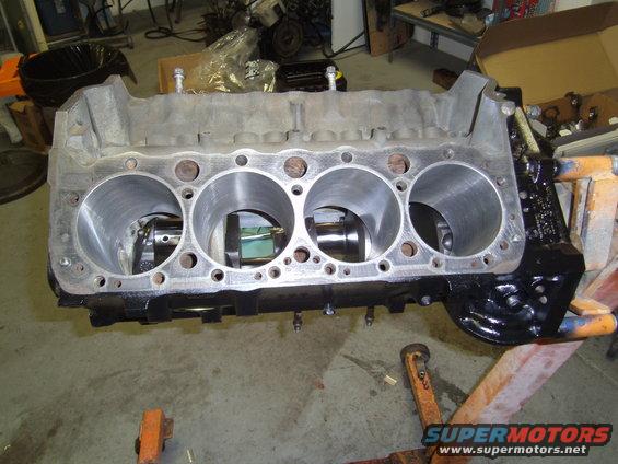 Engine block on an orange engine stand, showing four cylinders and internal components