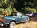 1990 Ford Bronco - A green Ford Bronco from the late 1980s is parked in a grassy area next to a white pickup truck.