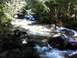 1990 Ford Bronco - A scenic view of a mountain stream, with water cascading over rocks and surrounded by lush greenery.