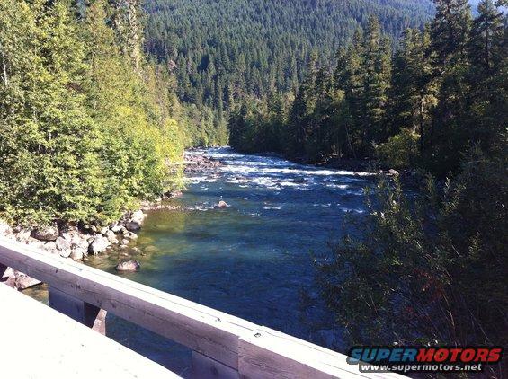 View of a river flowing through a forest, seen from a wooden bridge