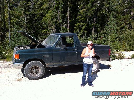 Dark green 1990 Ford Bronco with hood open, woman giving thumbs up