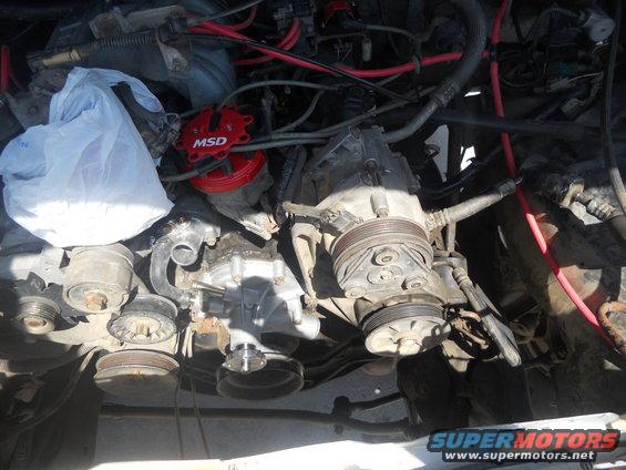 Engine bay with red MSD distributor cap, AC compressor, and various hoses and belts