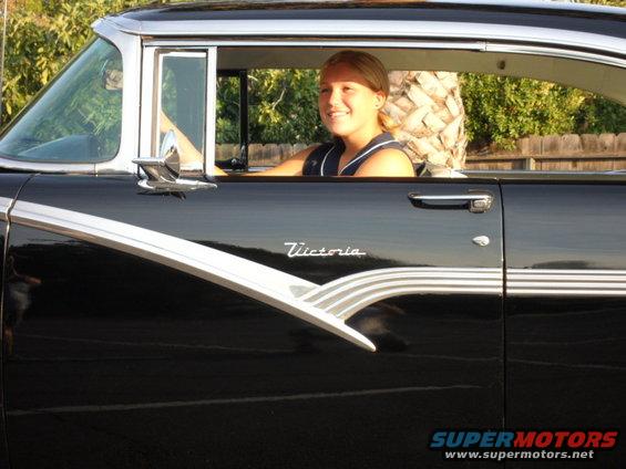 1956 Ford Fairlane Victoria with woman driver. Side view shows chrome trim and black paint