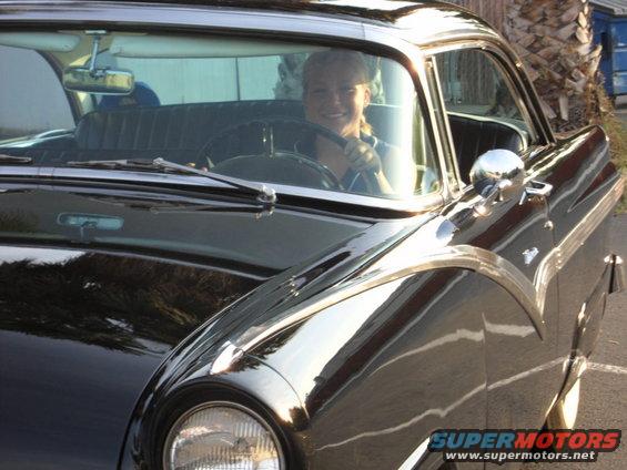 Woman smiling behind the wheel of a 1956 Ford Fairlane