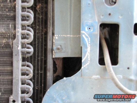 Radiator fins and light blue painted metal structure with white dotted lines and a white hose