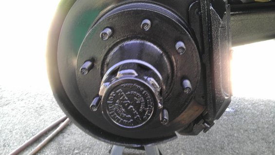 Close-up of a vehicle's front wheel hub and brake caliper assembly, painted black