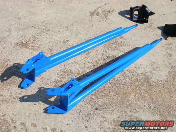 Two blue metal suspension arms and a black bracket on concrete