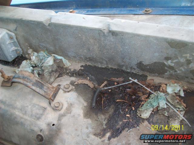Engine bay with dirt, leaves, and rags. Date stamp 09/14/2011
