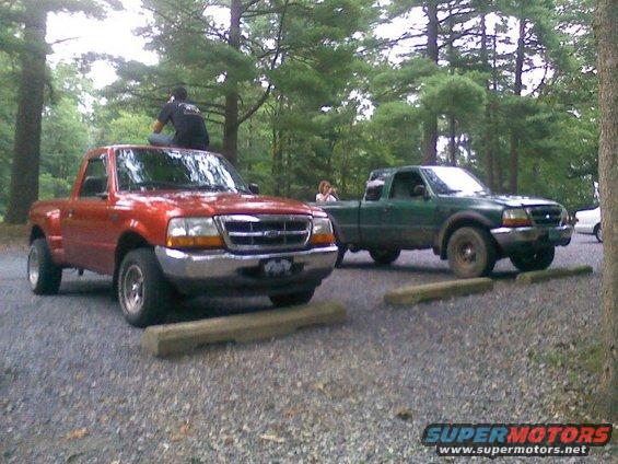 Red and green Ford Ranger pickup trucks parked side-by-side in a gravel lot