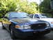 2003 Ford Crown Victoria - A blue 2003 Ford Crown Victoria is parked in front of another Crown Victoria.
