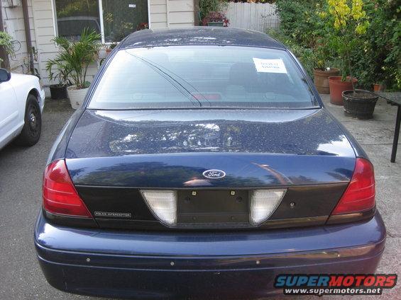 Rear view of a dark blue Ford Crown Victoria Police Interceptor, parked next to a white car