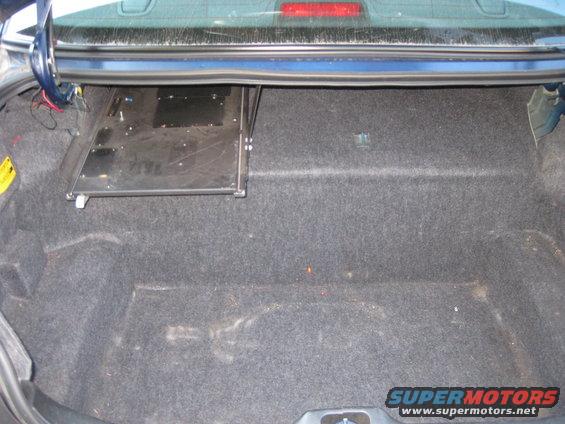 Car trunk with carpet lining and a metal tray mounted on the side