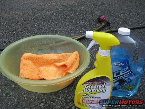 Orange microfiber towel in a yellow bowl next to Greased Lightning cleaner and Turtle Wax Ice car wash soap