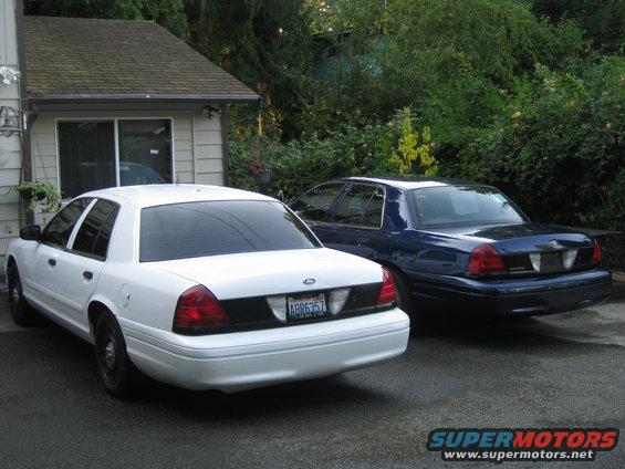 White and blue 2003 Ford Crown Victoria police cars parked in a driveway