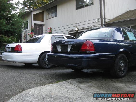 Rear view of blue 2003 Ford Crown Victoria next to white one