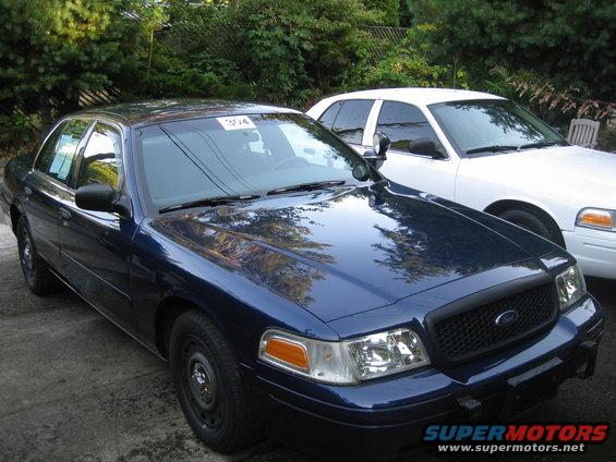 Dark blue 2003 Ford Crown Victoria parked next to a white 2003 Ford Crown Victoria
