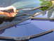 2003 Ford Crown Victoria - A hand holds a windshield wiper over the hood of a blue car, with several other wipers visible.