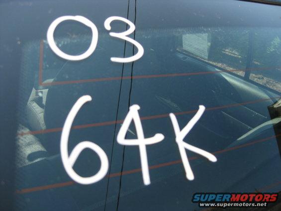 White text '03 64K' on rear window of 2003 Ford Crown Victoria